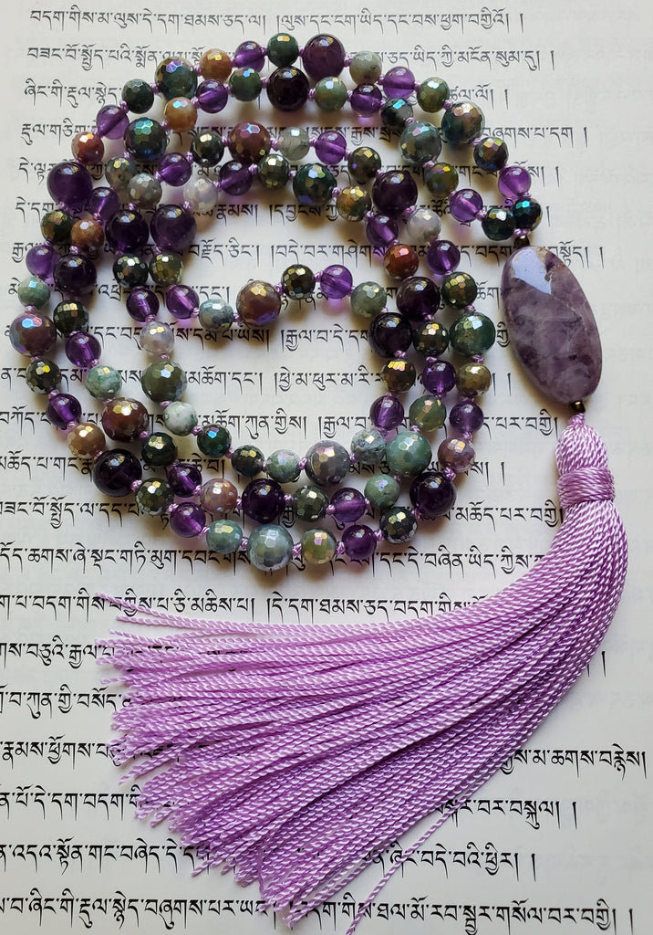 Full view of purple Amethyst and faceted, rainbow-plated Jasper beads that shimmer in shades of light green, lavender, and light brown. A purple and white Chevron Amethyst guru with lavender sutra and tassel brings this design full circle.