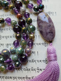 Close up view of oval, 15x30mm Chevron Amethyst guru, a blend of purple and white. Lavender tassel brings this design full circle.
