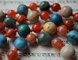 Close up view of bold orange Fire Agate, Bright Blue Apatite, turquoise Cuprite, and earthy tones of Fossil jasper beads. A brilliant orange, hand-knotted sutra brings all of these beautiful beads together.