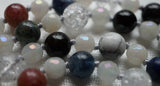 close up view of Pink tourmaline, dark blue Lapis Lazuli, white Howlite with gray inclusions, Black Tourmaline, Cracked Quartz Crystal, and light blue Kyanite beads. 6mm faceted White Jade. Dove gray knots between each bead showcase and protect the beads.