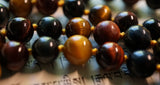close up view of Red Tiger Eye. Blue Tiger Eye. Gold Tiger Eye beads. goldenrod sutra (cord). knotted mala.